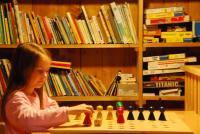 a young girl playing chess in a library at Bio Ferienbauernhof Greber in Schwarzenberg
