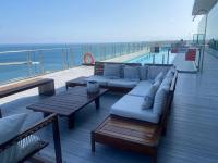 um deck com um sofá e mesas e o oceano em Urban Suites Apart Hotel con Estacionamiento Gratuito em Antofagasta