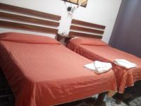 Dos camas en una habitación con sábanas rojas y zapatillas blancas. en Hotel Viña del Mar, en Lázaro Cárdenas