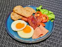a blue plate of food with eggs bacon tomatoes and bread at Mantra Beach Condominium Suite 2 - Mae Phim in Ban Tha Fat