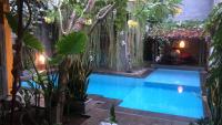 una piscina en un jardín con árboles y plantas en Nextdoor Rooms, en Yogyakarta