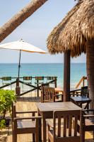 a beach with tables and chairs and an umbrella at Casa Lu Hotel Boutique in Mazunte