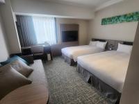 una habitación de hotel con dos camas y un sofá en Hotel Emisia Tokyo Tachikawa, en Tachikawa