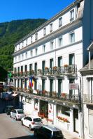 a large white building with cars parked in front of it at Hôtel Panoramic in Luchon