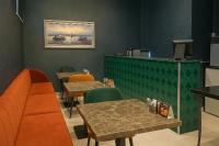 Un restaurante con dos mesas, un banco y un mostrador. en AXU AIRPORT HOTEL, en Arnavutköy