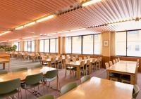 una grande stanza con tavoli, sedie e finestre di 蔵王ライザウッディロッジ a Kaminoyama