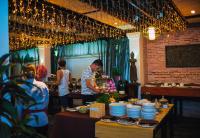 Un hombre de pie junto a una mesa con platos encima. en Angkor Land House, en Phumĭ Réach Born (2)