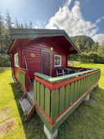 Cabaña roja pequeña con terraza en el césped en Sjøholt Camping, en Sjøholt