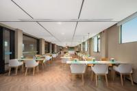 a row of tables and chairs in a cafeteria at Home2 Suite by Hilton Xishuangbanna Jinghong in Jinghong