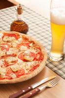 una pizza sentada en una mesa junto a un vaso de cerveza en Gostilna in picerija Harlekin, en Ribnica