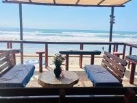 a patio with two benches and a table and the beach at Casa de las Olas Surf & Beach Club in Acapulco
