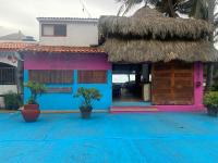a house with a thatched roof and blue and pink at Casa de las Olas Surf & Beach Club in Acapulco