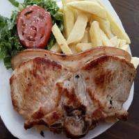 een bord eten met een stuk vlees en frietjes bij Hospedaje Hacienda Norabuena in Recuay