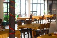 Madandanにあるwisma rotterdamの木製のテーブルと椅子と窓のあるレストラン