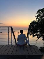 Una donna seduta su un molo che guarda l'acqua di Zanzibar,Fumbatown 2 Bed Ocean view Apartment a Fumba