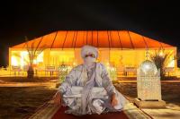 a person sitting on a rug in front of a building at Global Luxury Camp in Merzouga