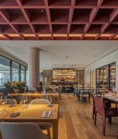 a restaurant with wooden tables and chairs and windows at MACAM Hotel in Lisbon