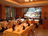 un restaurant avec des tables et des chaises blanches et des fenêtres dans l'établissement Hotel Ariston ***S, à Madonna di Campiglio