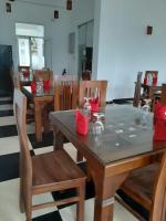 uma sala de jantar com mesas de madeira e cadeiras com guardanapos vermelhos em Hotel Kenrish em Wadduwa
