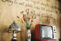 Un pequeño televisor sobre una mesa con un jarrón con flores. en Bến Thành Market - KAS HOTEL, en Ho Chi Minh