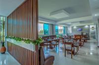Un restaurante con mesas, sillas y ventanas. en KRM Hotel - Caran, en Kampala