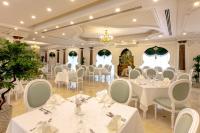 Un salón de banquetes con mesas y sillas blancas. en Sunset Jeddah, en Yeda