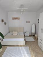 Un dormitorio blanco con una cama y un espejo. en Cozzy Studio Tirana, en Tirana