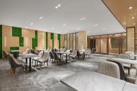 un restaurante con mesas, sillas y paredes verdes en 麗枫酒店广州白云国际机场空港店 Lavande Hotel Guangzhou Baiyun Airport Branch, en Huadu