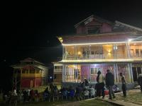 un grupo de personas de pie fuera de una casa por la noche en Neelum Resorts Taobat, en Taobat