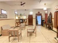 a living room with chairs and a couch and a tv at La Ruelle Guest House in Puducherry