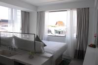 a white bedroom with a bed and a window at Riva Arun Bangkok in Bangkok