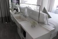 a white bathroom with a sink and a bed at Riva Arun Bangkok in Bangkok