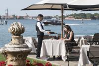een man en een vrouw zitten aan een tafel voor het water bij San Clemente Palace Venice in Venetië