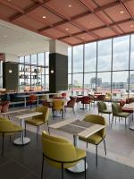 Un restaurante con mesas y sillas y grandes ventanales. en The Quarter Ramkhamhaeng by UHG, en Bangkok