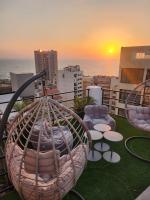 un balcón con sillas, mesas y una puesta de sol en Palm Ville Suites, en Beirut