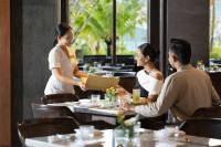 um grupo de pessoas sentadas às mesas de um restaurante em Lampung Marriott Resort & Spa em Lampung