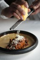 una persona sosteniendo un trozo de queso sobre un plato de comida en Hotel Hans, en Copenhague