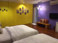 a bedroom with two beds and a purple and yellow wall at Pottery B&amp;B in Jiaoxi
