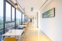 City Comfort Inn Hainan Haikou Wanghai International Plaza Qilou Old Street Branch في هايكو: صف من الطاولات والكراسي في غرفة مع نوافذ كبيرة