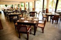 カタラガマにあるFarm Villa By Heritageの木製のテーブルと椅子と窓のあるレストラン