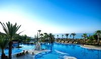 a large swimming pool with palm trees and the ocean at Four Seasons Hotel in Limassol