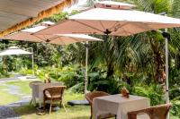 two tables and chairs with umbrellas in a garden at Wan'an Tinglan Wild Luxury Resort Hotel in Jinghong