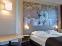 ラーティンゲンにあるB&amp;B Hotel Düsseldorf-Ratingenのベッドと壁に絵が飾られたホテルの部屋