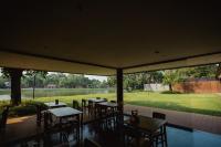 Un restaurante con mesas y sillas y un gran ventanal. en The Grandiose Hotel Chiang Rai เดอะแกรนด์ดิโอสเชียงราย, en Chiang Rai