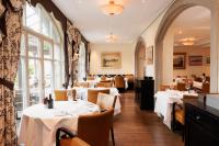 キュスナハトにあるBoutiquehotel Sonne Küsnacht - Zürichの白いテーブルと椅子と窓のあるレストラン