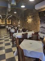 um restaurante com mesas e cadeiras brancas e uma parede de tijolos em Trpeza Prenociste em Požarevac