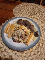 ein Teller mit Essen mit Fleisch und Brot auf einem Tisch in der Unterkunft Pousada Praia Bonita Em Milagres in São Miguel dos Milagres