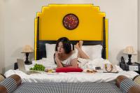 una mujer acostada en una cama con un plato de comida en Grand Fusion Point Hotel, en Hue