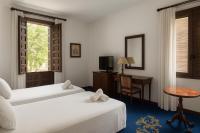 Una habitación de hotel con dos camas, un escritorio y un televisor. en Hotel El Bedel, en Alcalá de Henares