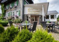 Un restaurante con mesas y sillas frente a un edificio. en Hotel Forsthaus, en Winterberg